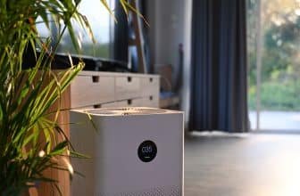 Air purifier with digital monitor screen and house plant in living room for fresh air.