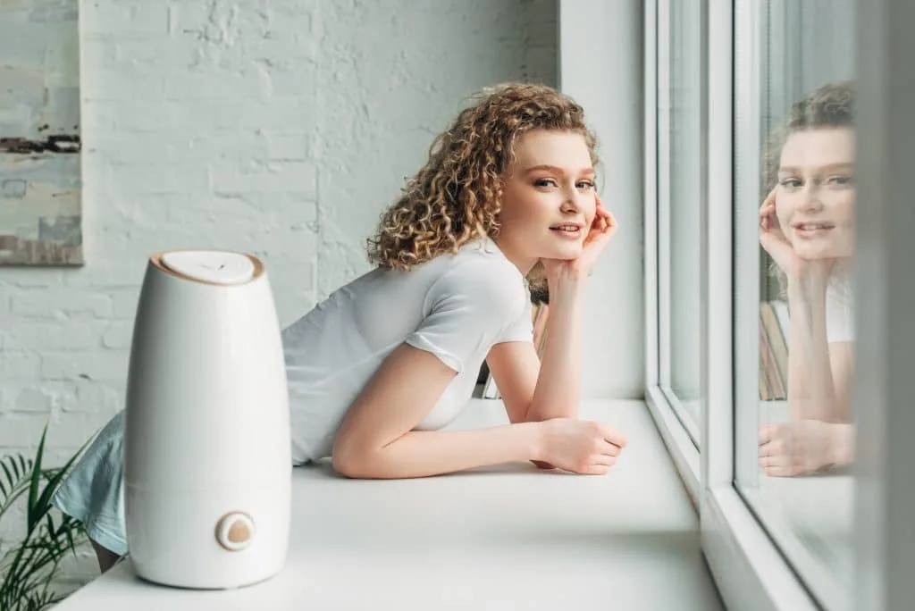 smiling girl with ultrasonic air purifier on windowsill