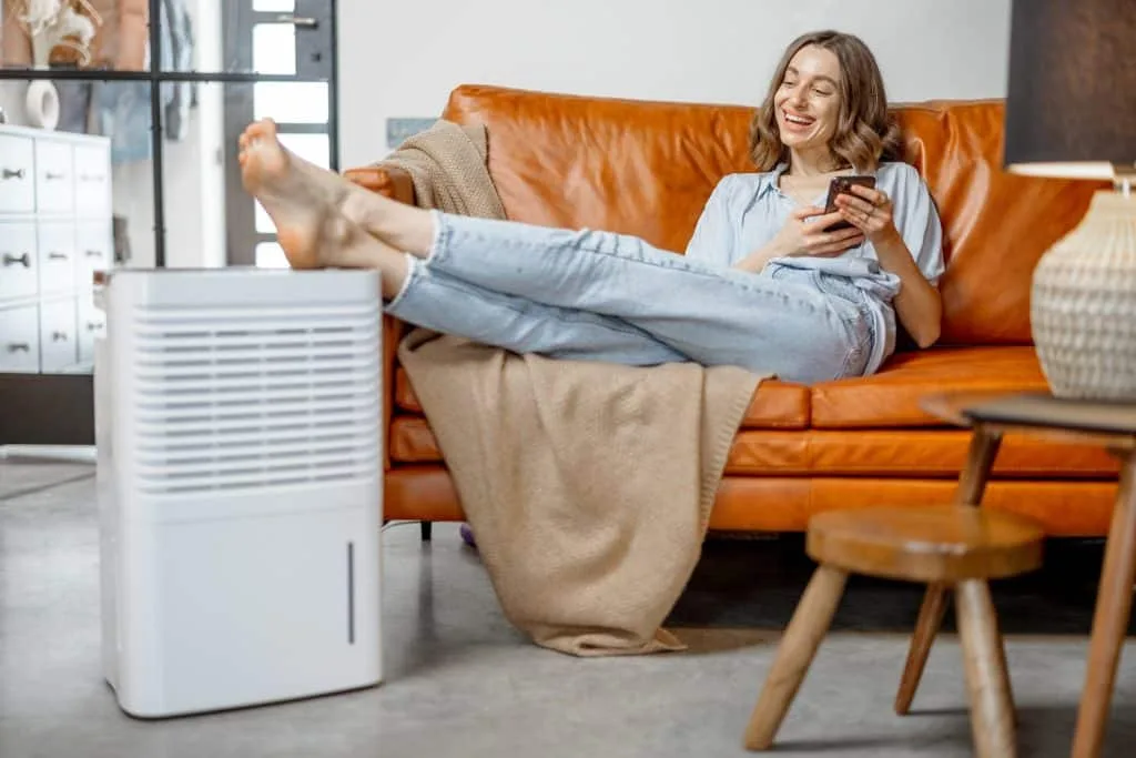 Woman sitting near air purifier and moisturizer appliance