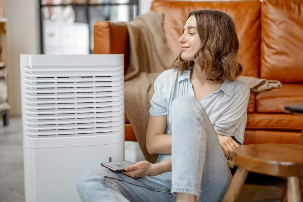 Woman sitting near air purifier and moisturizer appliance