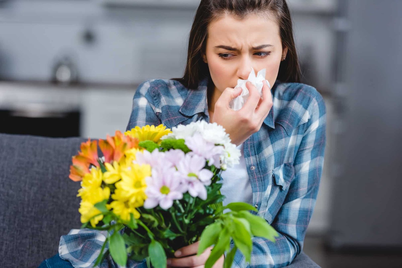 girl with allergy holding facial tissue and looking at flowers